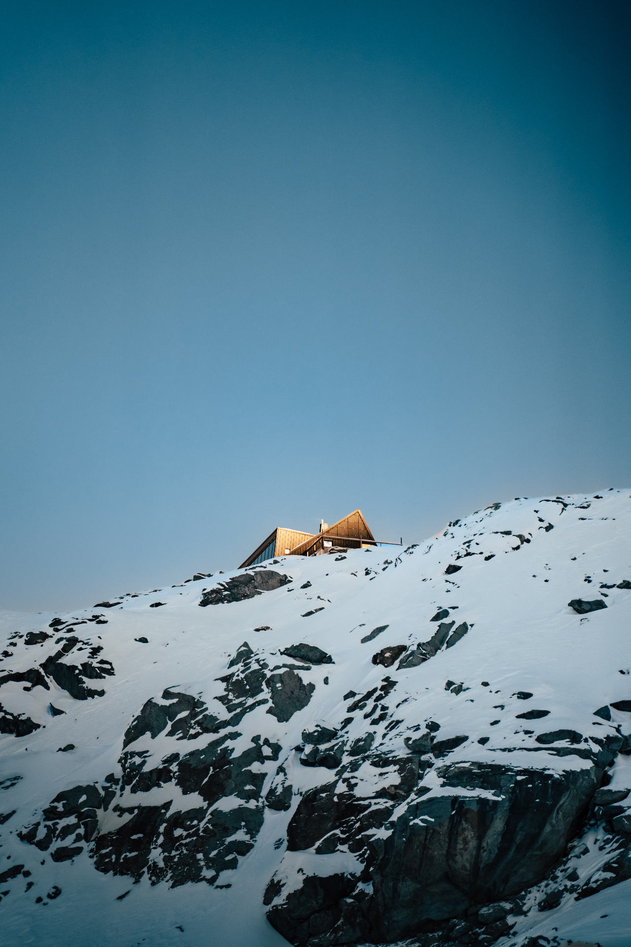 Cabane Tortin sustainable off-grid architecture at sunset, showcasing the glass, timber, and stone design perched at 3,000 metres in the Swiss Alps with golden light on surrounding peaks